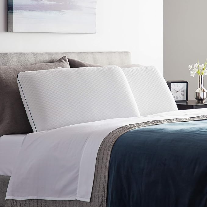 A bed featuring a white cover and blue WEEKENDER Gel Memory Foam Pillows, creating a cozy and inviting atmosphere.