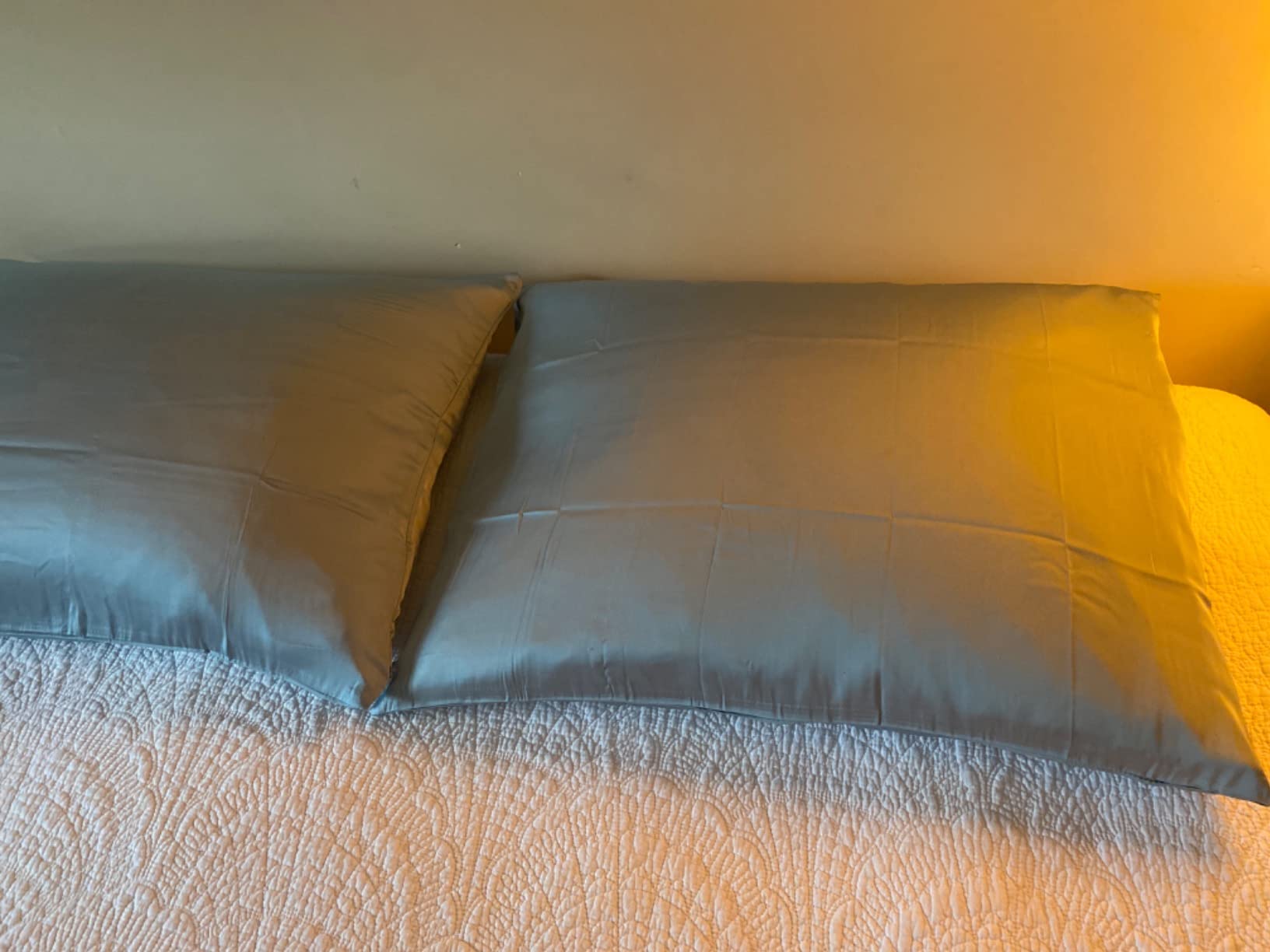 Two blue pillows on a bed with a lamp, showcasing the Natural Mulberry Silk Pillowcase in use for a product review.