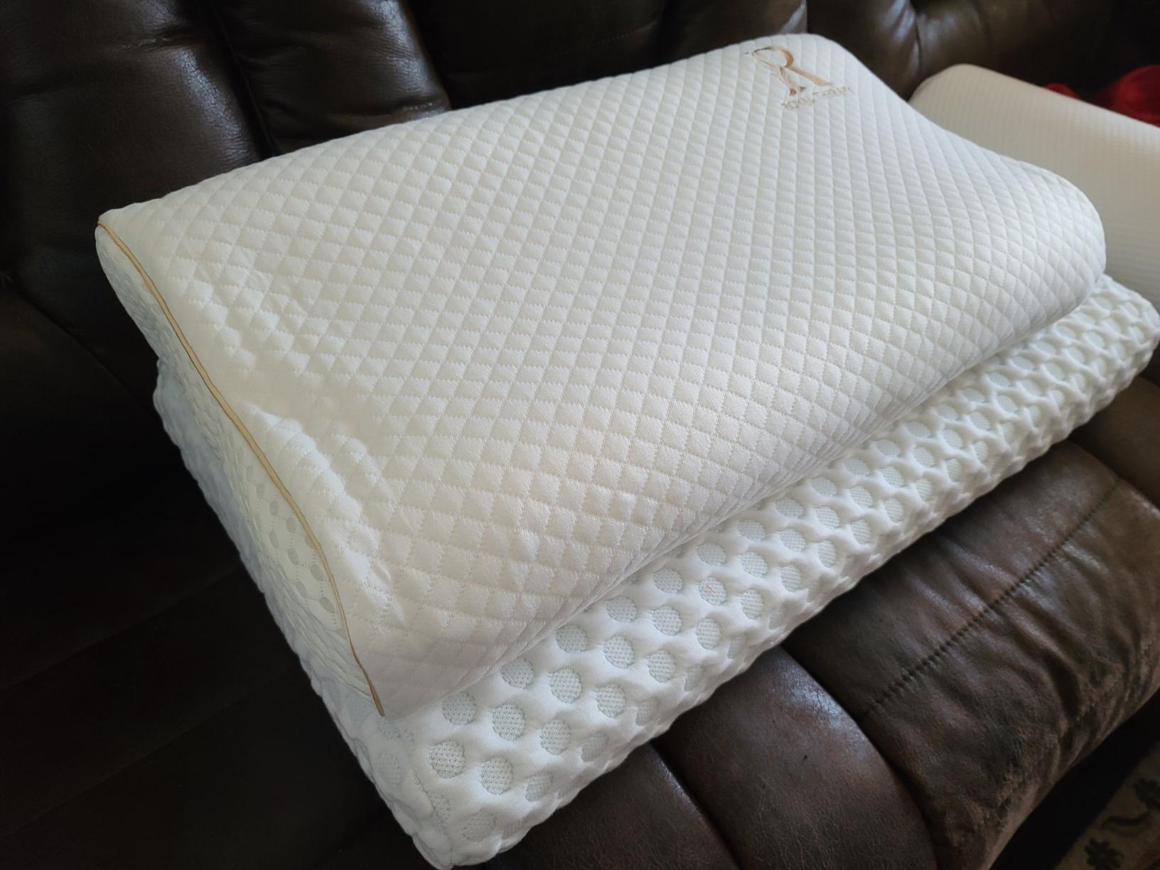 The Royal Therapy Memory Foam Pillow is placed on a couch with a white cover, highlighting its design and comfort for review.
